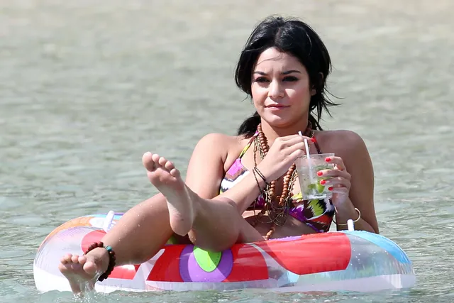Vanessa Hudgens floating on an inflatable with bare feet visible.