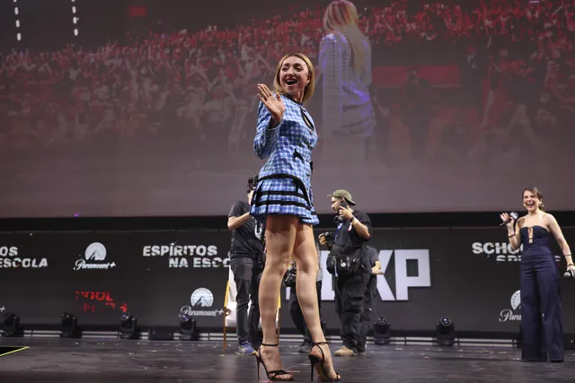 Peyton List wearing black heels and a blue dress onstage.