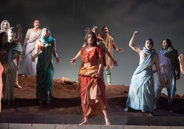 Anya Chalotra performing barefoot onstage among other actors.
