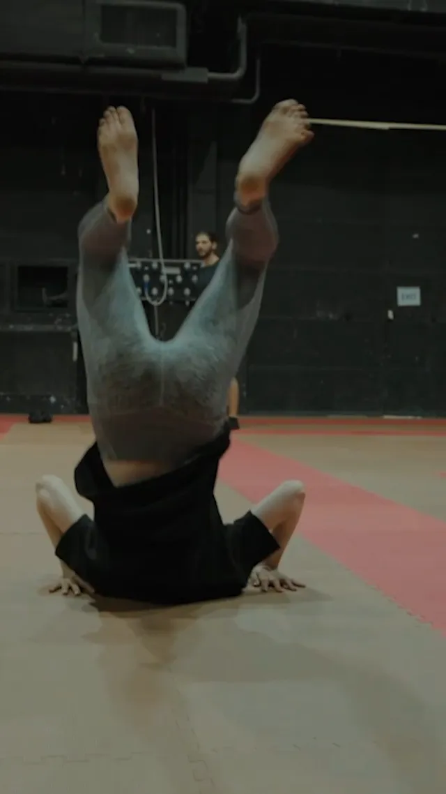 Emma Myers rolling backward barefoot on a training mat.