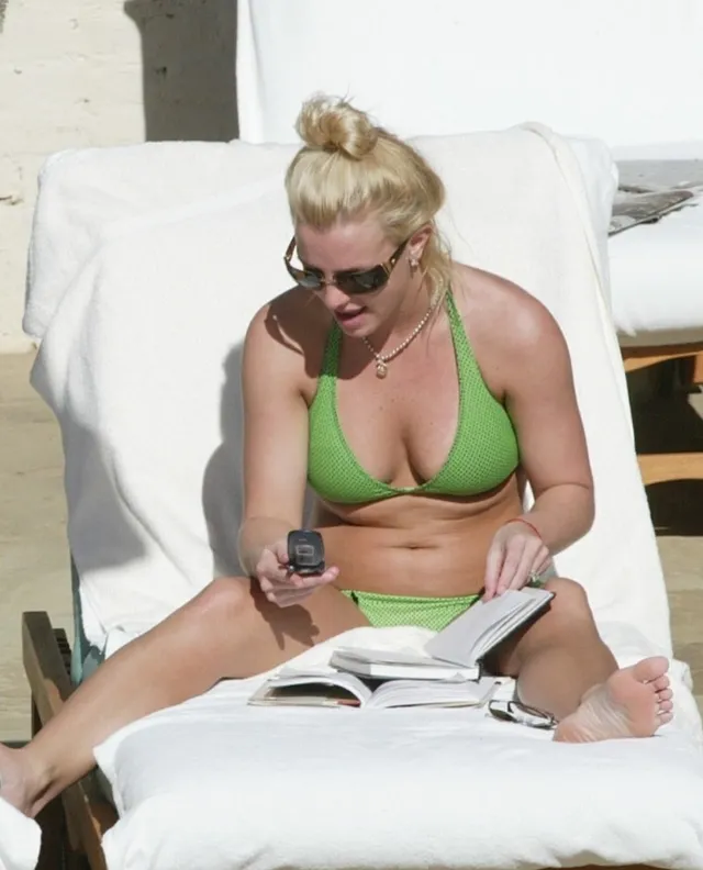 Britney Spears a green swimsuit while seated on a white sunbed.
