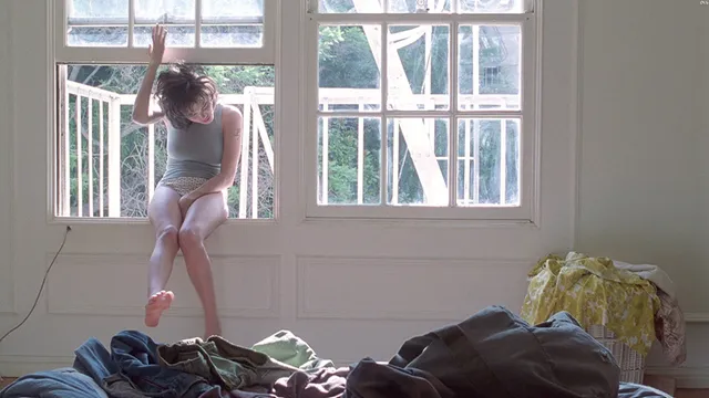 Angelina Jolie seated beside a window with a bare foot raised in a screen scene.