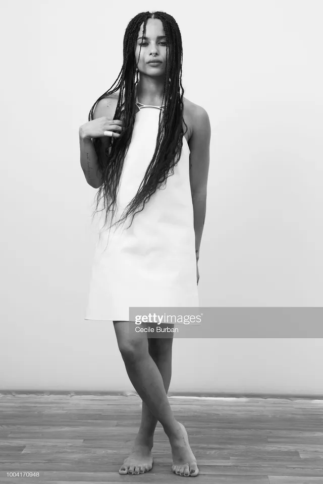 Zoë Kravitz standing in a monochrome portrait in a white dress.