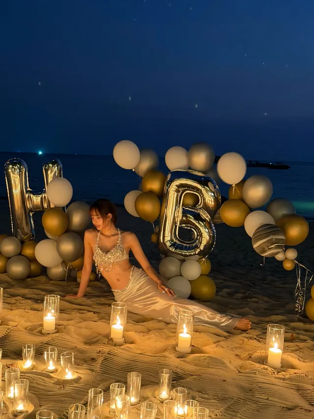 Lisa (Lalisa Manobal) kneeling barefoot on a beach beside birthday balloons and candles.