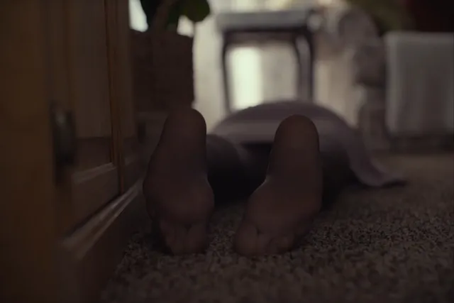 Daisy Ridley lying on a carpet in a dramatic screen scene.