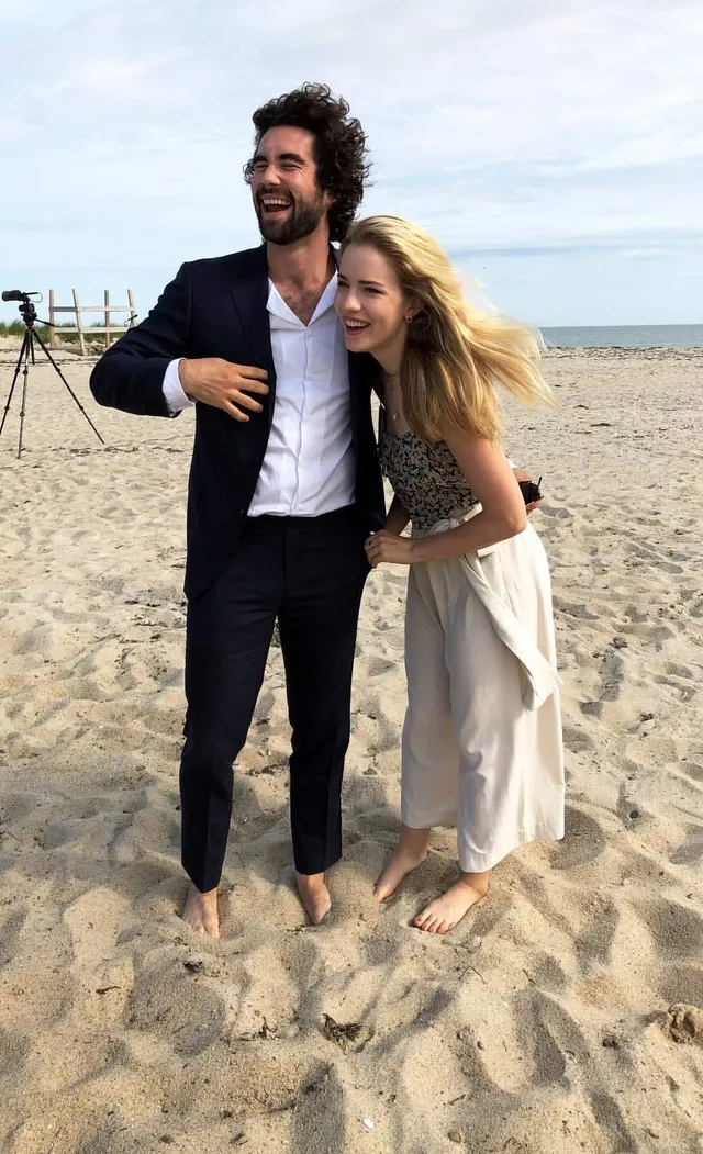 Willa Fitzgerald standing barefoot on a beach with a companion.