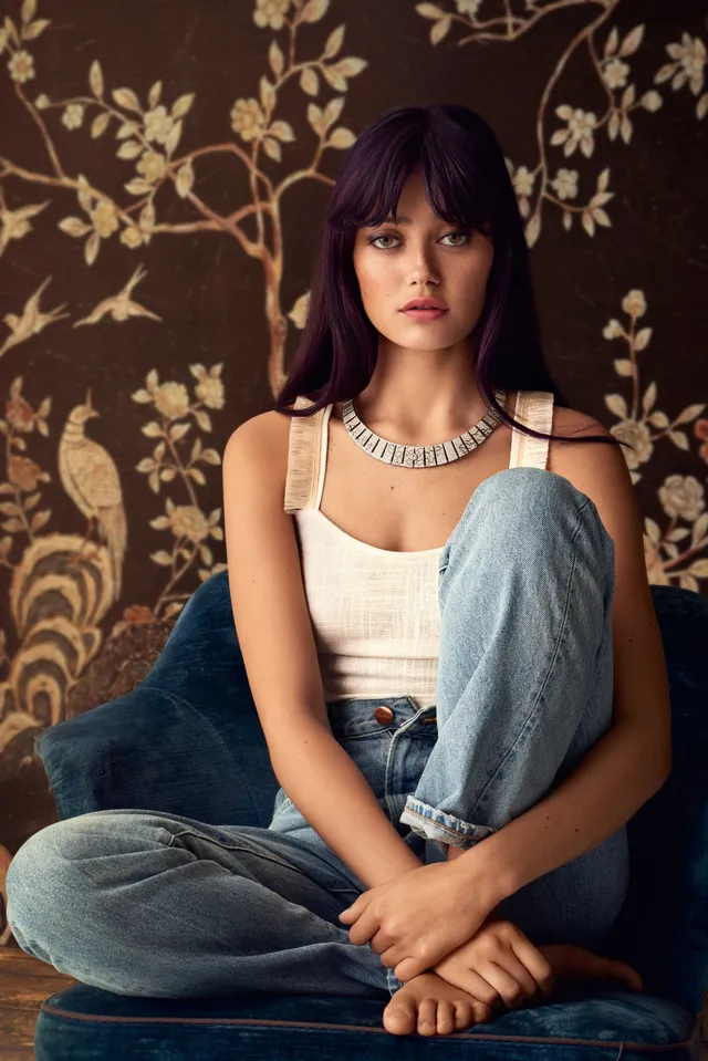 Ella Purnell sitting cross legged in jeans for a portrait.