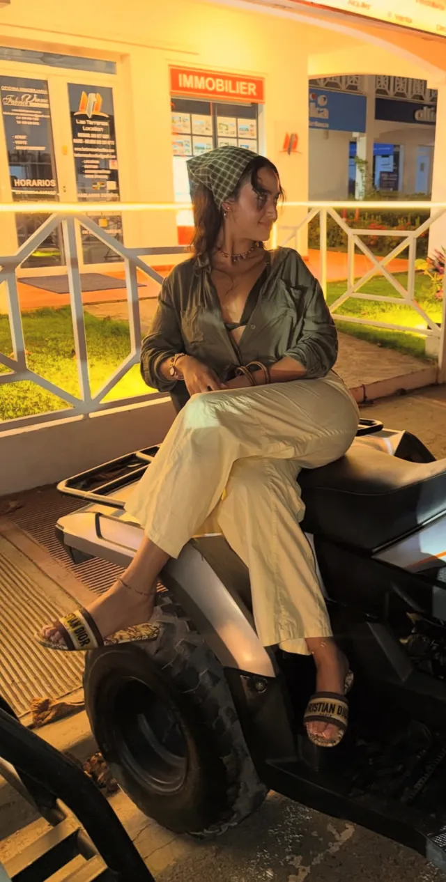 Emily Tosta sitting in a small vehicle wearing black heels.