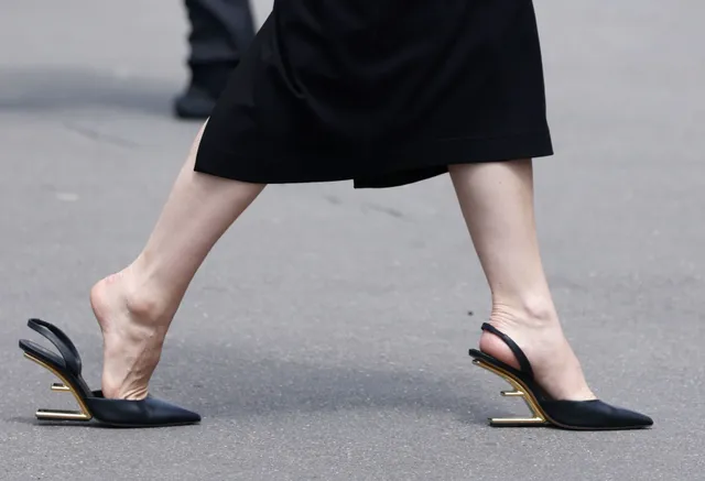 Lily James walking in black slingback heels in side view.