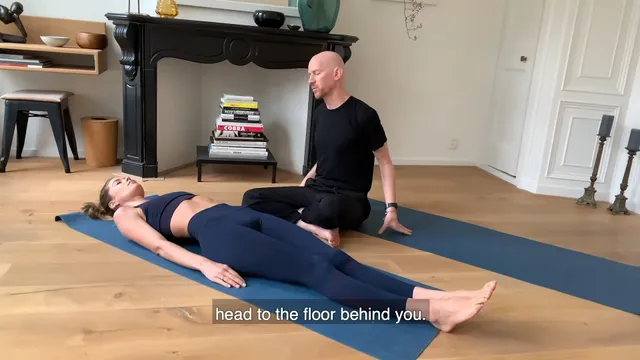 Doutzen Kroes reclining barefoot on an exercise mat with an instructor.