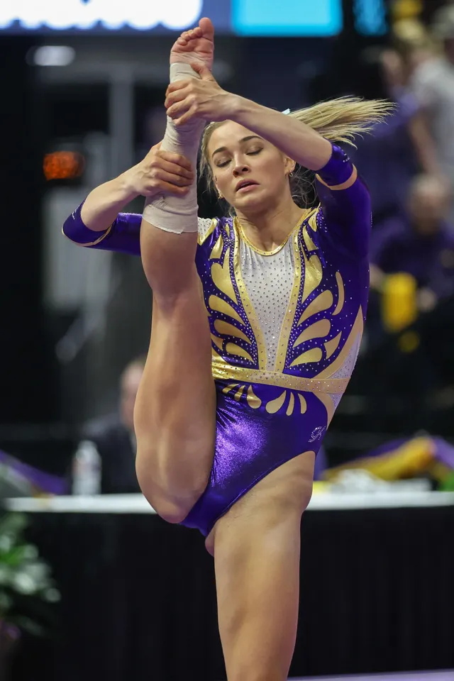 Olivia Dunne: holding one bare foot overhead during a gymnastics routine.
