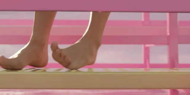 Margot Robbie showing bare feet in a pink film set close up.