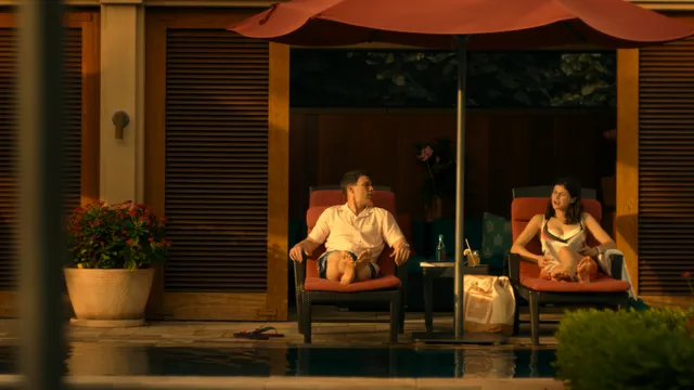 Alexandra Daddario sitting barefoot on an outdoor patio in a scene.