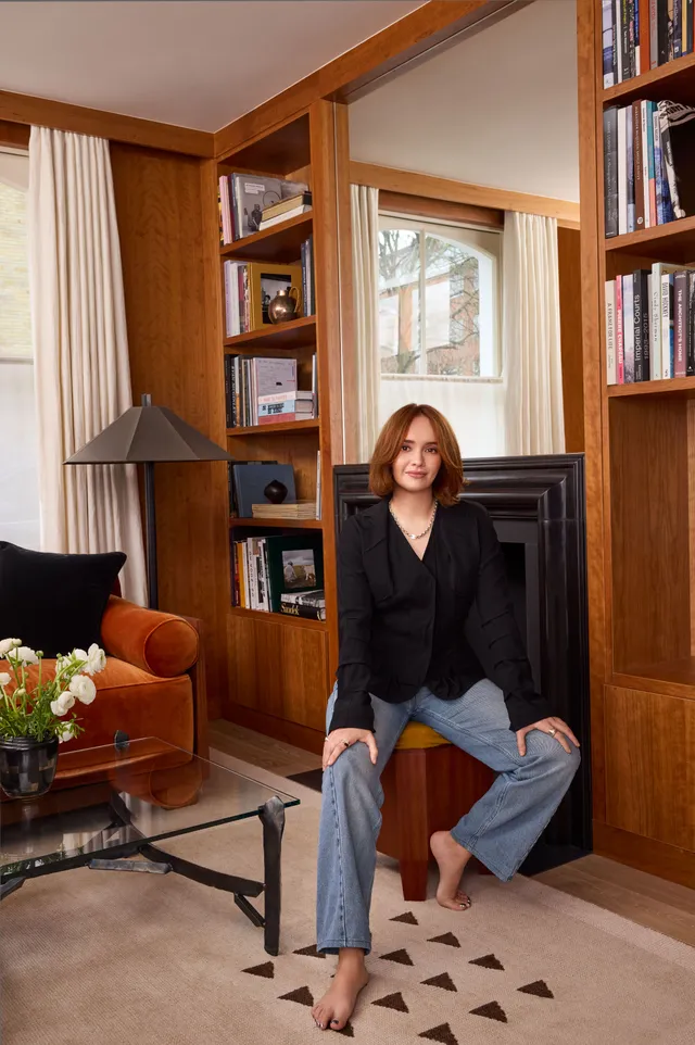 Olivia Cooke sitting in a wood panelled room in jeans and a jacket.
