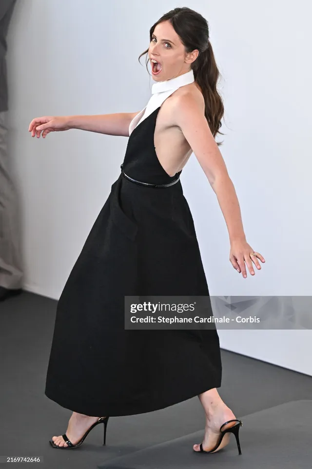 Felicity Jones walking at a film festival in a black dress.