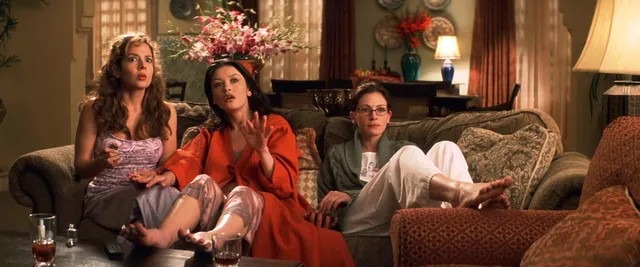 Catherine Zeta-Jones a seated screen scene on a sofa beside other characters.