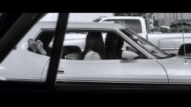 Rosario Dawson sitting inside a car with her feet raised.