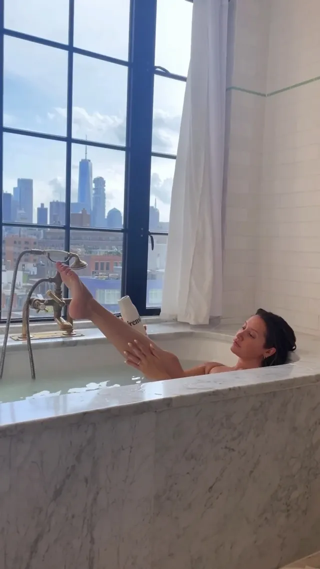 Ashley Tisdale raising her bare legs while reclining in a bath.