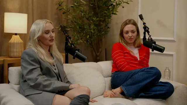Amanda Seyfried sitting barefoot on a couch in a red striped top.