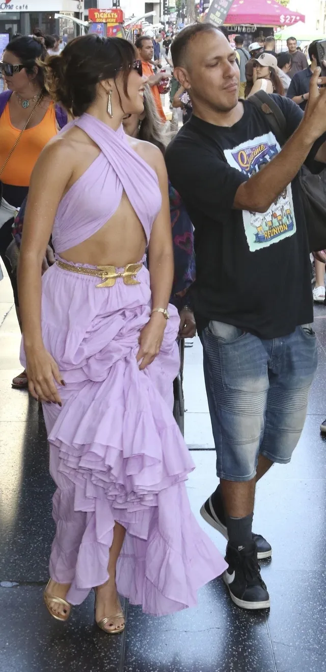 Xochitl Gomez standing beside other people in a purple dress and heels.