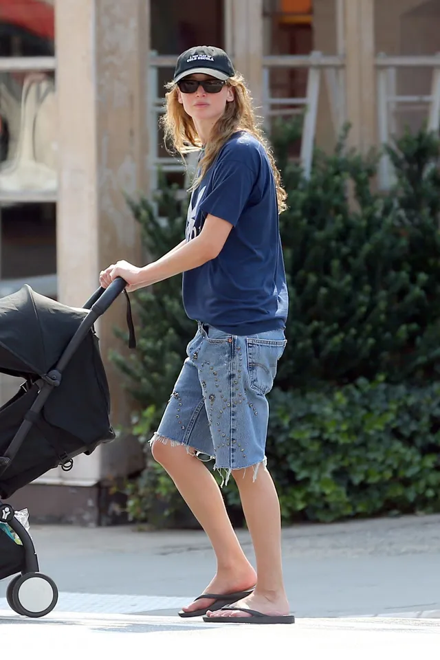Jennifer Lawrence walking outside with a stroller in flat sandals.