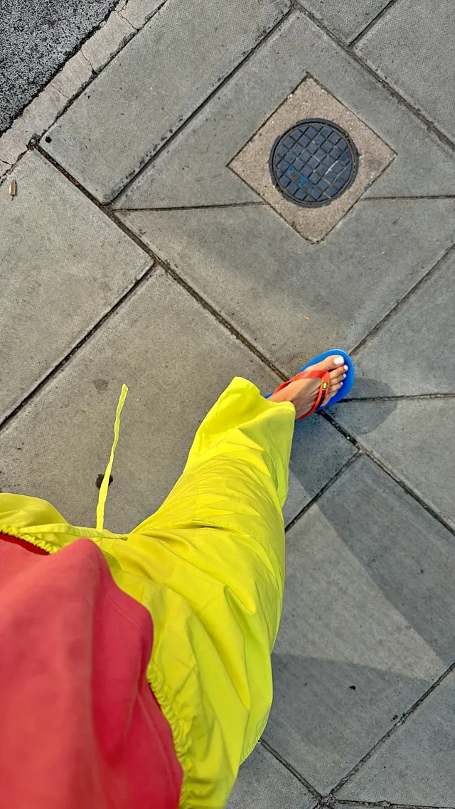 Rita Ora wearing bright trousers and blue flip-flops.