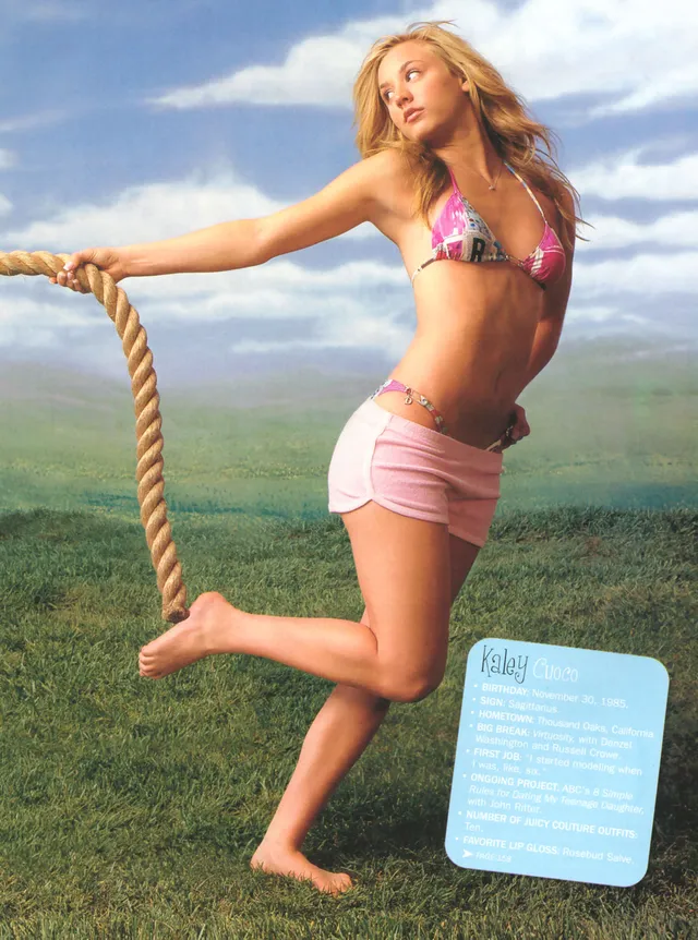 Kaley Cuoco standing on grass beside a rope with one bare foot raised.