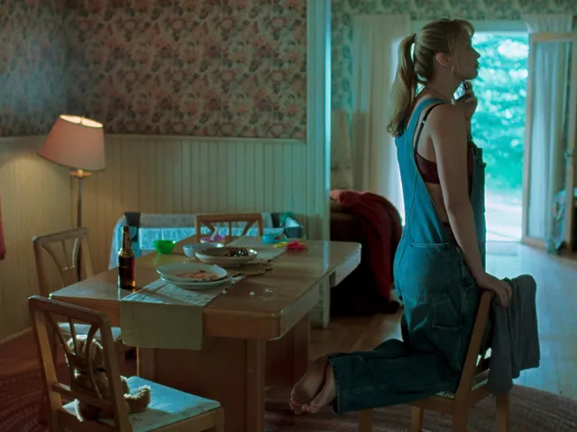 Jennifer Lawrence standing barefoot beside a dining table in a screen scene.