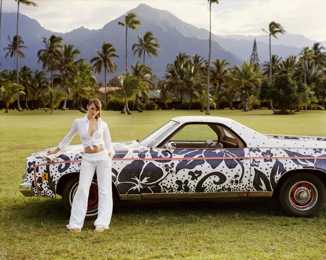 Jennifer Garner standing beside a patterned car in a white outfit.