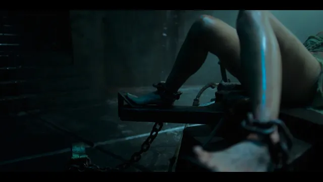 Freya Allan with boots visible in a dimly lit film scene.