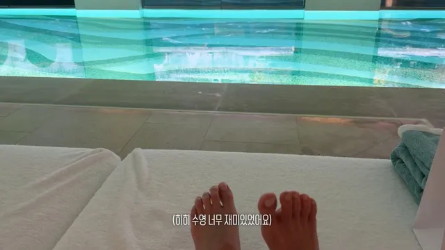 Jisoo resting her bare feet on a lounger beside a swimming pool.