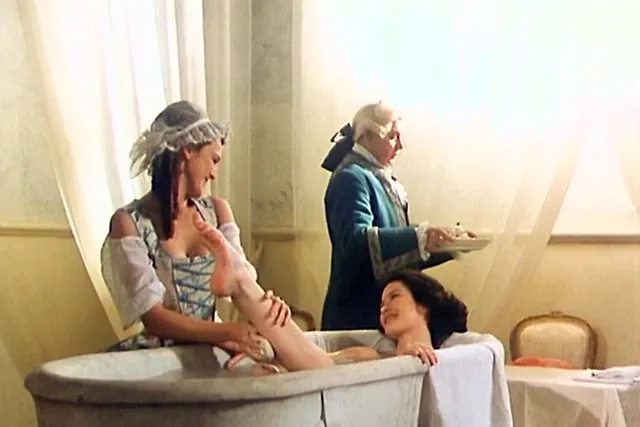 Catherine Zeta-Jones a seated screen scene on a stone bench.
