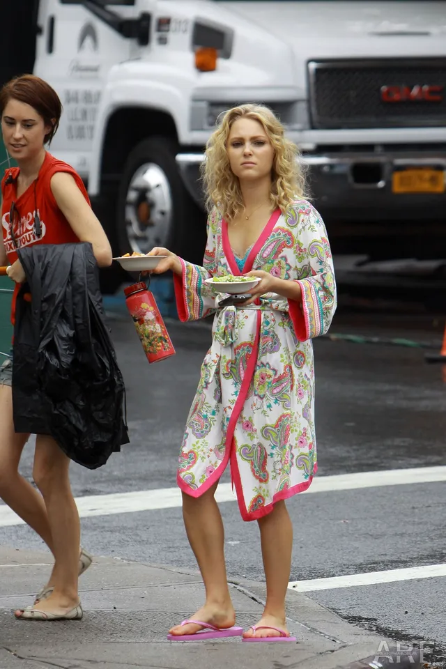 AnnaSophia Robb standing by a vehicle in a patterned robe and flip-flops.