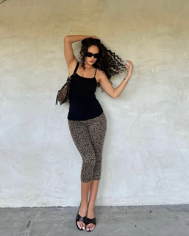 Madison Pettis posing in a dark top, leopard-print skirt and black heels.