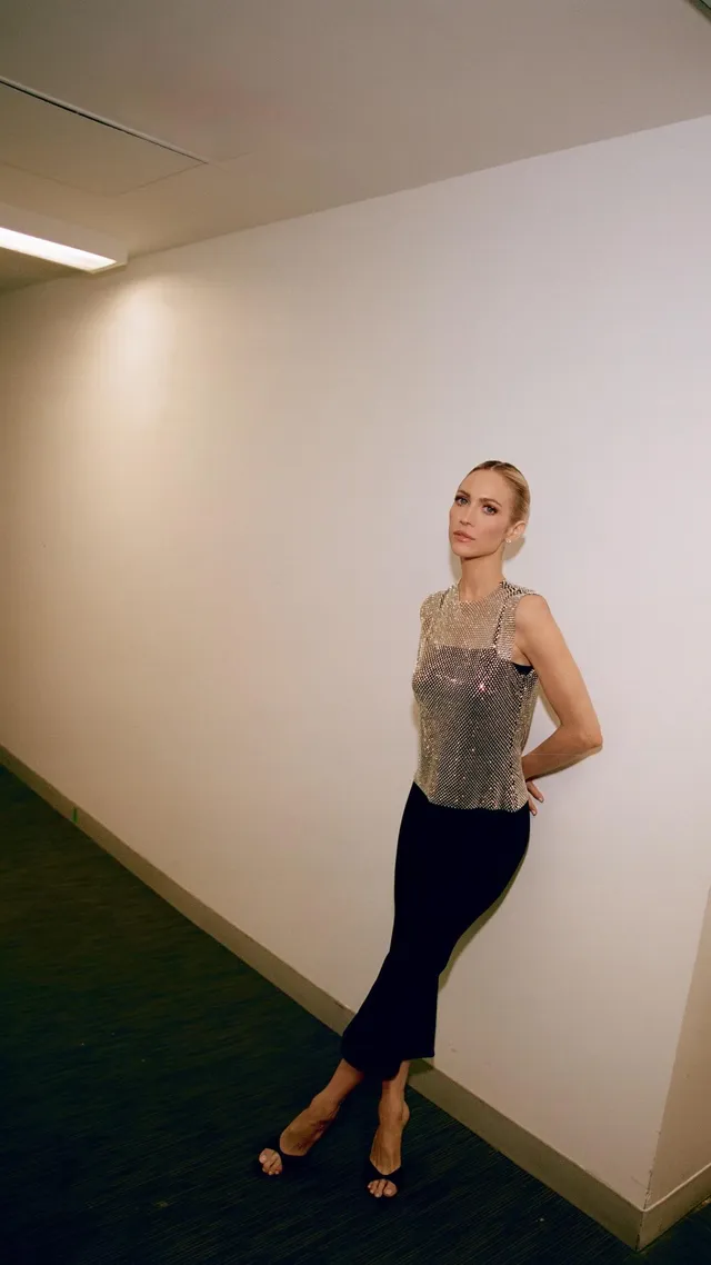 Brittany Snow posing indoors in a patterned top and dark trousers.