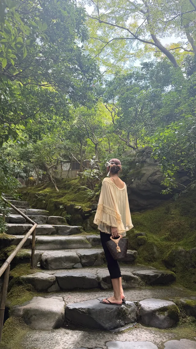Lisa (Lalisa Manobal) standing barefoot on garden stone steps in dark cropped trousers.