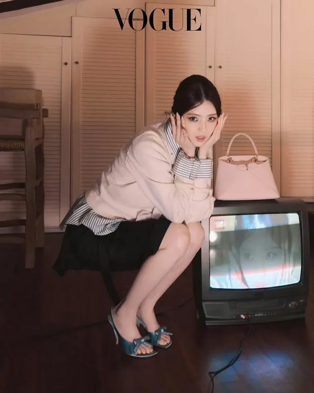 Han So-hee sitting beside a television in heeled sandals.