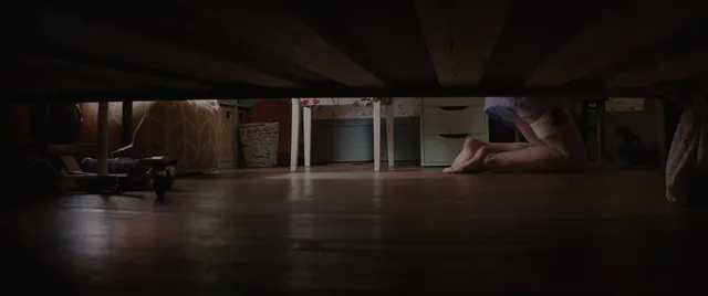 Chloë Grace Moretz bare feet visible beneath a bed in a film scene.