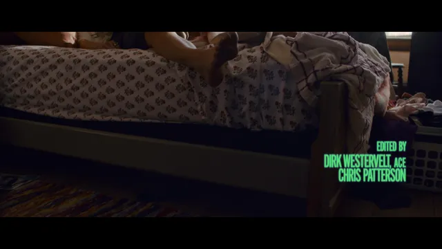 Samara Weaving resting bare feet over the side of a bed in a film scene.
