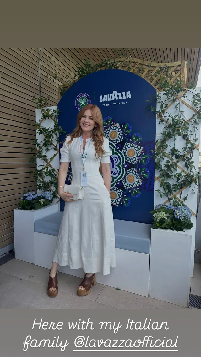 Isla Fisher standing outdoors in a white outfit.