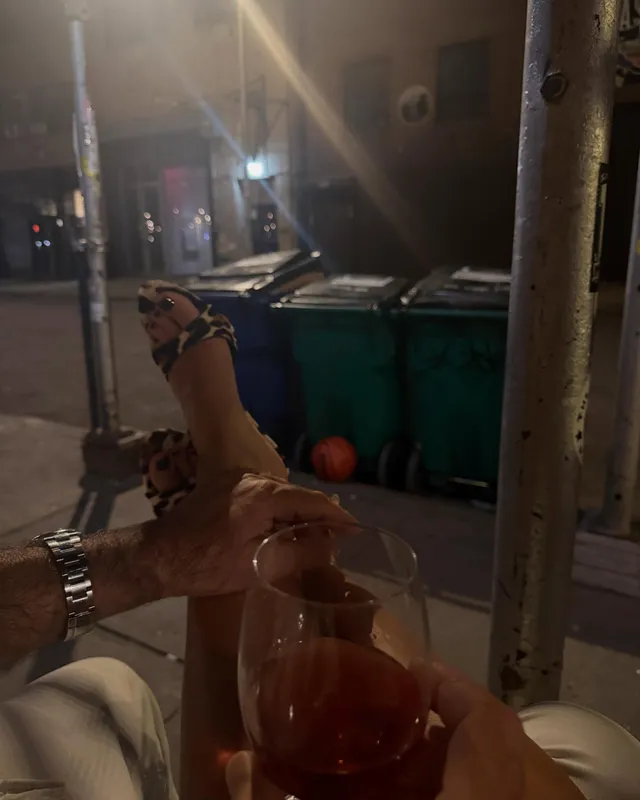 Emily Ratajkowski resting a bare foot beside a drinks table.
