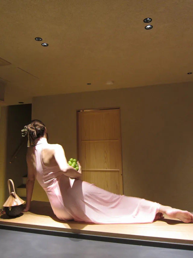 Lisa (Lalisa Manobal) sitting barefoot in a window alcove wearing a long pink dress.