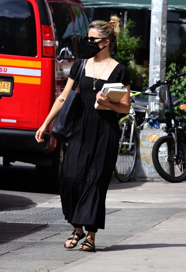 Dianna Agron carrying takeaway containers in a black dress.