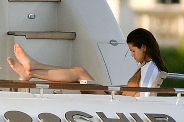 Selena Gomez sitting with her feet raised on a boat.