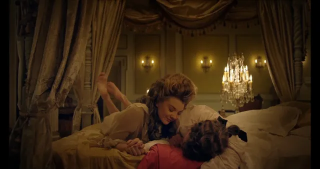 Natalie Dormer leaning over another character in a bedroom scene.