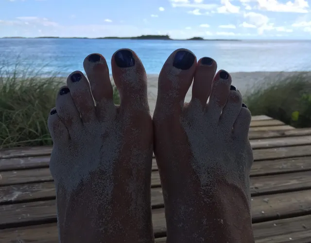Anna Kournikova resting her bare feet beside a seaside deck.