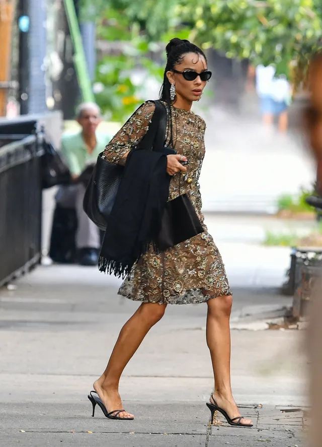 Zoë Kravitz walking outside in a patterned dress and black sandals.