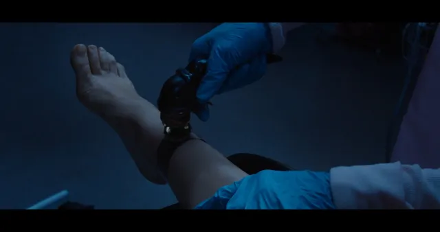 Mila Kunis showing a bare foot during a low-lit indoor scene.