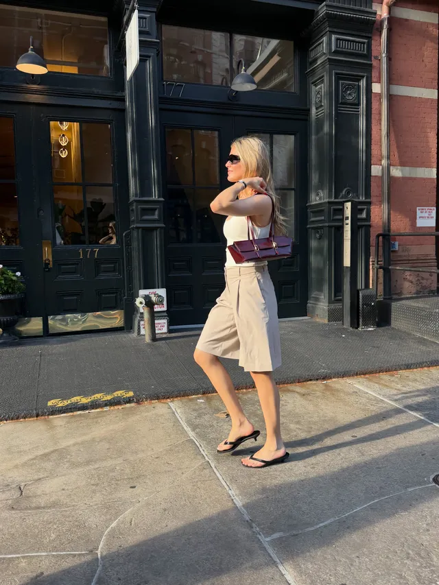 Eugenie Bouchard walking in black flat sandals and pale culottes.