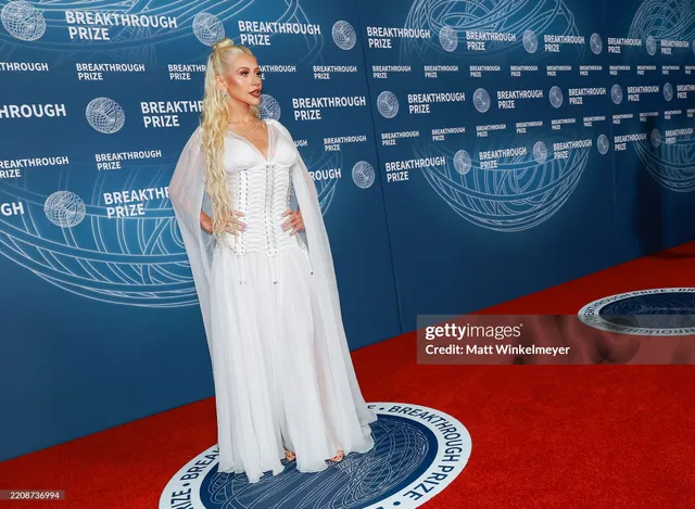 Christina Aguilera posing at an event in a long white gown.